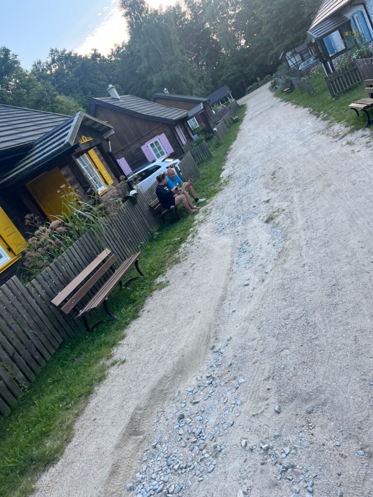 Piaszczysta droga wśród drewnianych domów z kolorowymi okiennicami w Przysiółku Spore